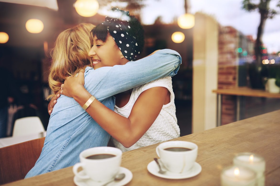 Ladies hugging in coffee shop