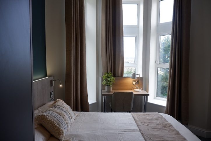 Double bed in front of a large bay window and desk