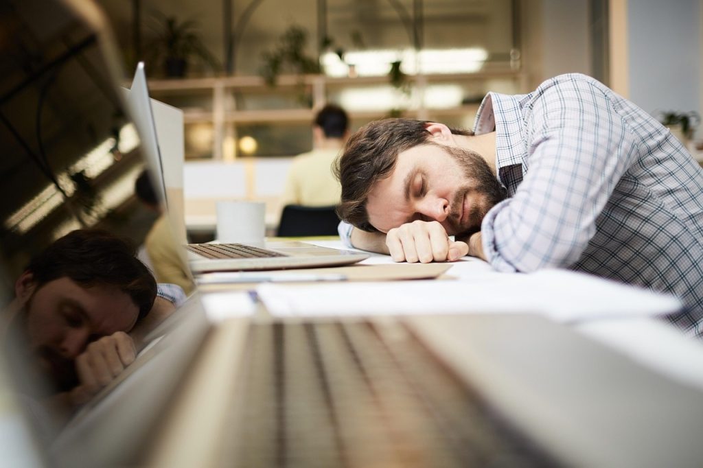 Office worker slumped over their desk asleep