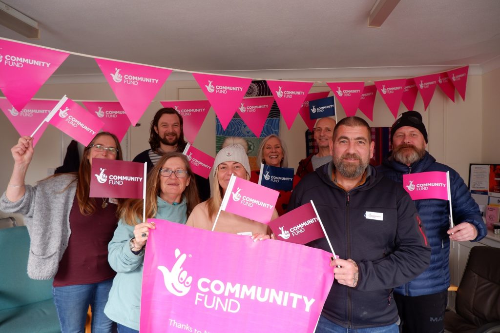 Group of people holding celebration flags with bunting on the wall