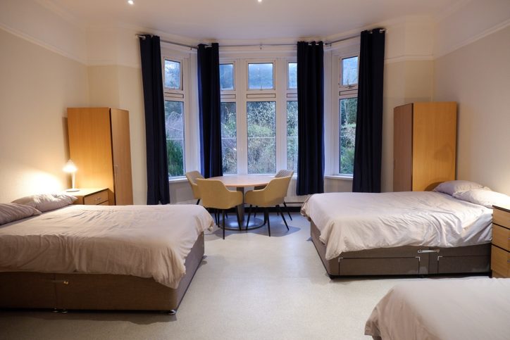 Large bedroom showing three double beds and large bay window