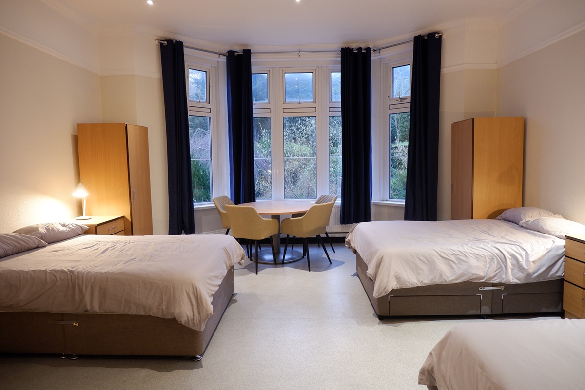 Large bedroom showing three double beds and large bay window